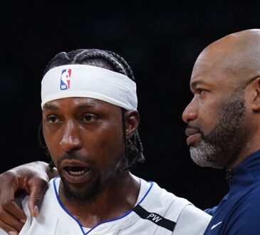 Orlando Magic head coach Jamahl Mosley drapes an arm over guard Kentavious Caldwell-Pope as they talk on the sideline.