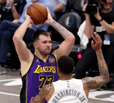 Luka Dončić looks to pass for the Los Angeles Lakers as P.J. Washington defends for the Dallas Mavericks at American Airlines Center