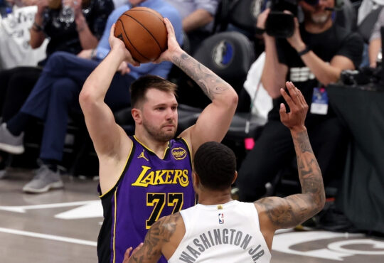 Luka Dončić looks to pass for the Los Angeles Lakers as P.J. Washington defends for the Dallas Mavericks at American Airlines Center