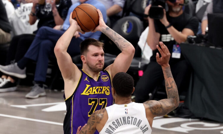 Luka Dončić looks to pass for the Los Angeles Lakers as P.J. Washington defends for the Dallas Mavericks at American Airlines Center