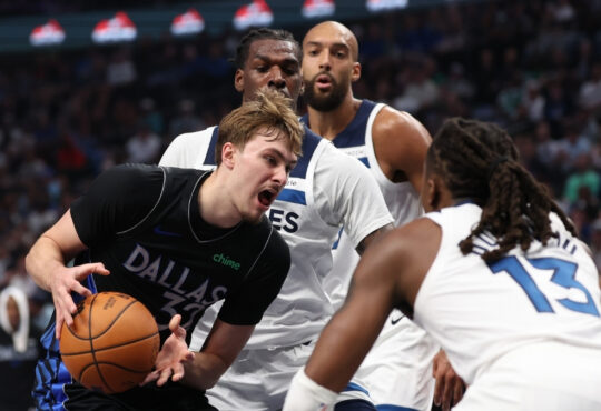 Cooper Flagg of the Dallas Mavericks drives against Ayo Dosunmu and Naz Reid of the Minnesota Timberwolves at American Airlines Center.