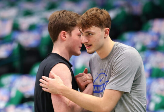Cooper Flagg #32 of the Dallas Mavericks and Kon Knueppel #7 of the Charlotte Hornets embrace on the court at American Airlines Center.