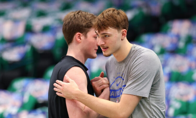 Cooper Flagg #32 of the Dallas Mavericks and Kon Knueppel #7 of the Charlotte Hornets embrace on the court at American Airlines Center.
