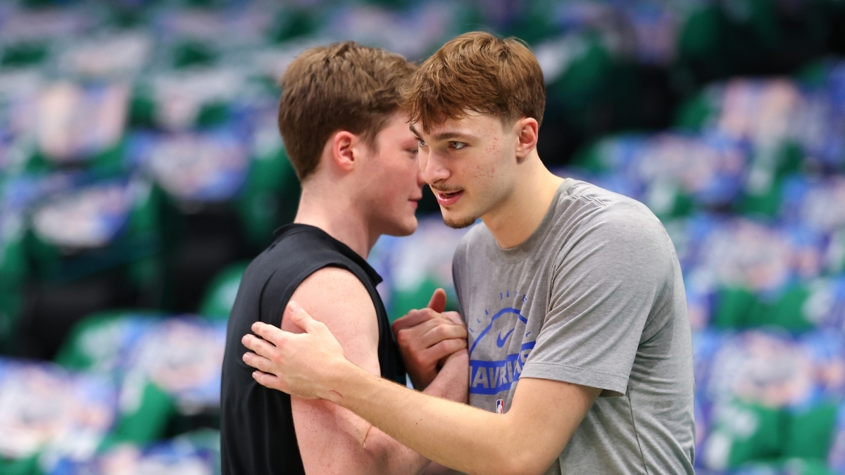 Cooper Flagg #32 of the Dallas Mavericks and Kon Knueppel #7 of the Charlotte Hornets embrace on the court at American Airlines Center.