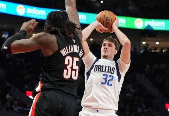 Cooper Flagg of the Dallas Mavericks shoots over Robert Williams III of the Portland Trail Blazers during the first half at Moda Center on March 27, 2026.