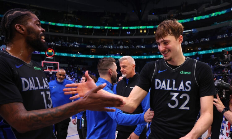 Naji Marshall #13 of the Dallas Mavericks greets Cooper Flagg #32 as they exit the court following a victory over the Los Angeles Lakers at American Airlines Center.
