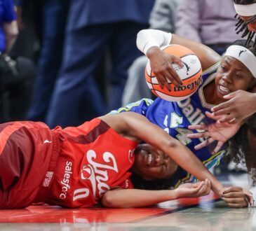Arike Ogunbowale (24) of the Dallas Wings and Kelsey Mitchell (0) of the Indiana Fever battle for a loose ball at Gainbridge Fieldhouse.
