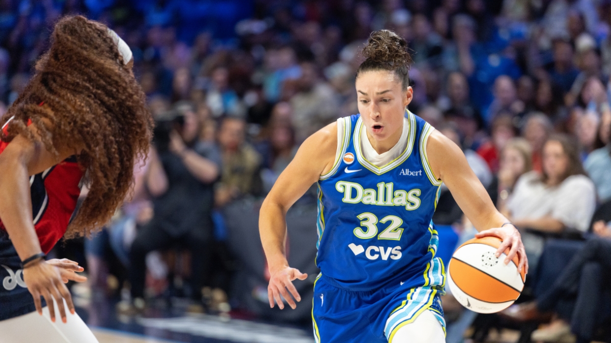 Jessica Shepard lowering her shoulder and dribbling the basketball with her right hand while driving past the tight perimeter defense of Kiki Iriafen.