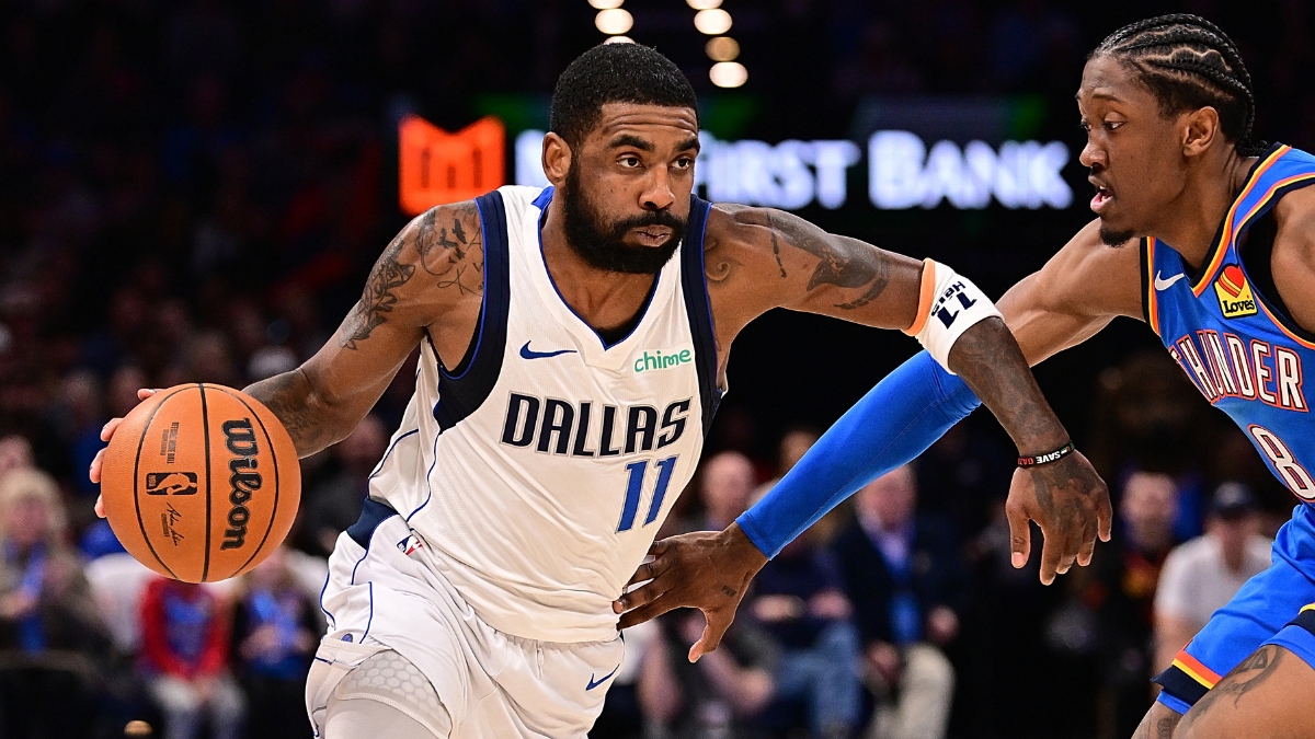 Guard Kyrie Irving wearing a blue Dallas Mavericks jersey while handling the ball on the perimeter against defender Jalen Williams of the Oklahoma City Thunder.