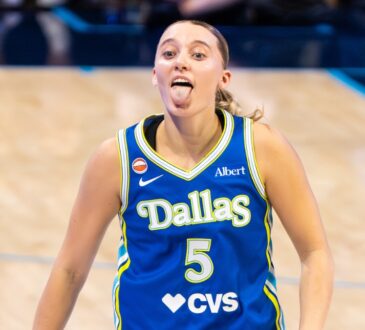 Guard Paige Bueckers celebrating on the court, smiling and gesturing dynamically after a successful offensive sequence.