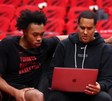 Toronto Raptors assistant coach and Mavericks head coaching candidate Jama Mahlalela reviews film on a laptop with forward Scottie Barnes on the bench