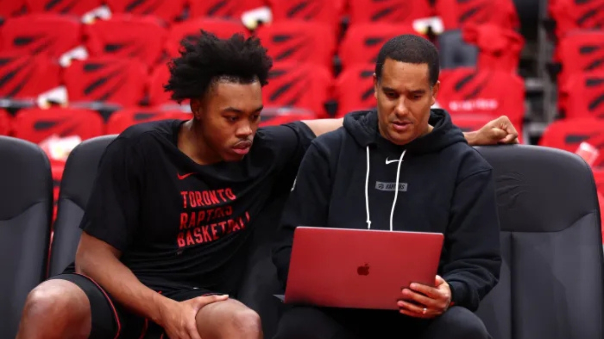 Toronto Raptors assistant coach and Mavericks head coaching candidate Jama Mahlalela reviews film on a laptop with forward Scottie Barnes on the bench