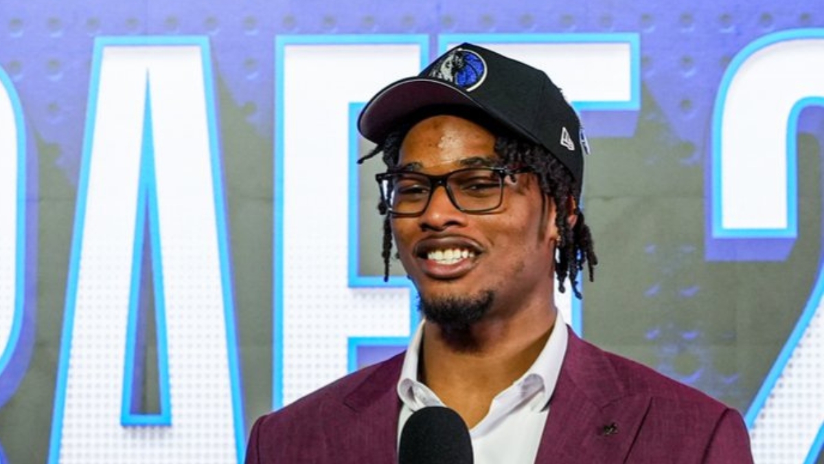 Morez Johnson Jr. smiles in a Dallas Mavericks cap and maroon suit while speaking on stage after being drafted No. 9 in the 2026 NBA Draft