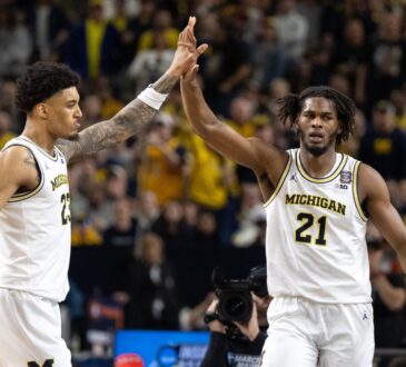 Morez Johnson Jr. in a white Michigan No. 21 jersey high-fives a teammate during the 2026 Final Four