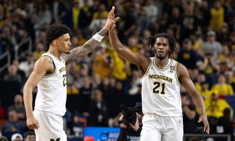 Morez Johnson Jr. in a white Michigan No. 21 jersey high-fives a teammate during the 2026 Final Four
