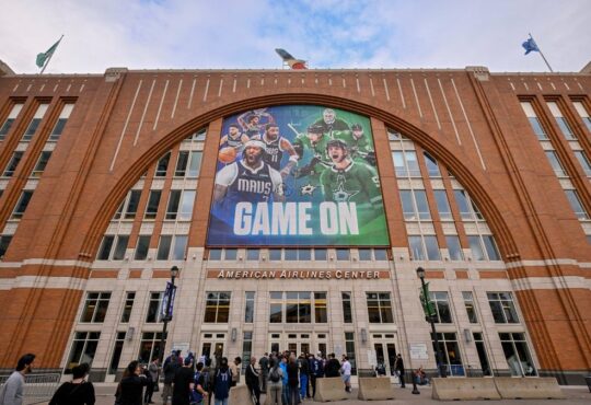 Exterior of American Airlines Center in Dallas, home of the Mavericks, with a Mavs and Stars banner above the west entrance