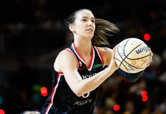Portland Fire forward Bridget Carleton rises into her shooting motion, holding an All-Star Wilson ball with a rack visible at left, during the 2026 State Farm WNBA 3-Point Contest at Wintrust Arena in Chicago.