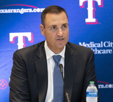 Texas Rangers general manager Chris Young speaks into a microphone in front of a Rangers backdrop at Globe Life Field.