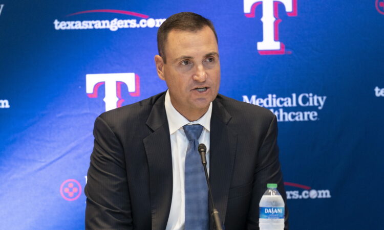 Texas Rangers general manager Chris Young speaks into a microphone in front of a Rangers backdrop at Globe Life Field.