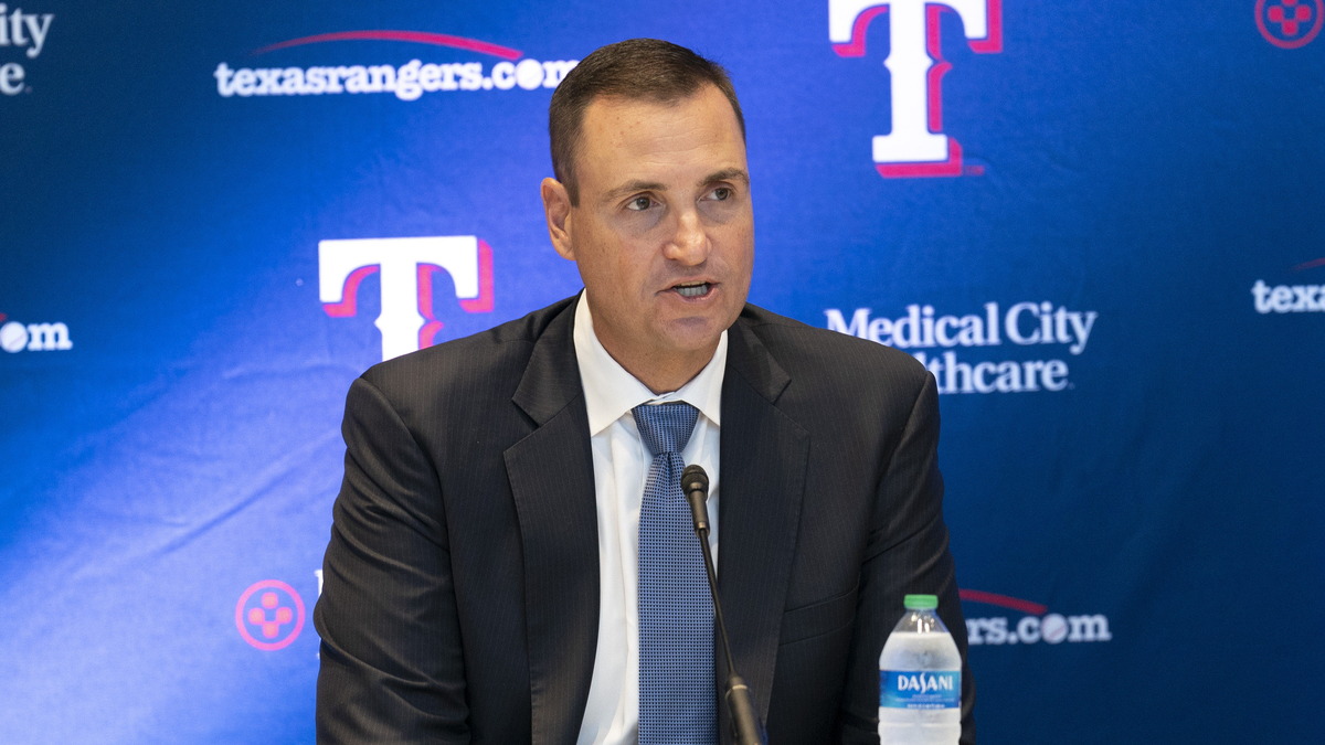 Texas Rangers general manager Chris Young speaks into a microphone in front of a Rangers backdrop at Globe Life Field.