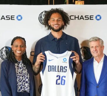 Dereck Lively II holds a Dallas Mavericks jersey with the Chase patch alongside Rick Welts and Pauline Saunders at the partnership announcement