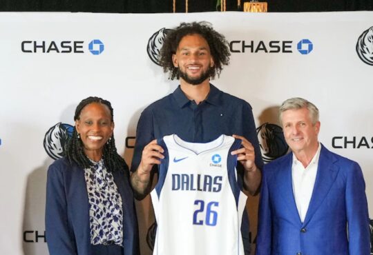 Dereck Lively II holds a Dallas Mavericks jersey with the Chase patch alongside Rick Welts and Pauline Saunders at the partnership announcement