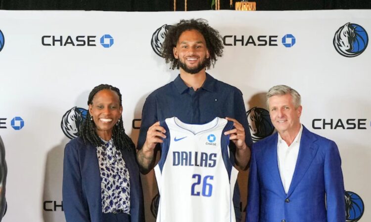 Dereck Lively II holds a Dallas Mavericks jersey with the Chase patch alongside Rick Welts and Pauline Saunders at the partnership announcement