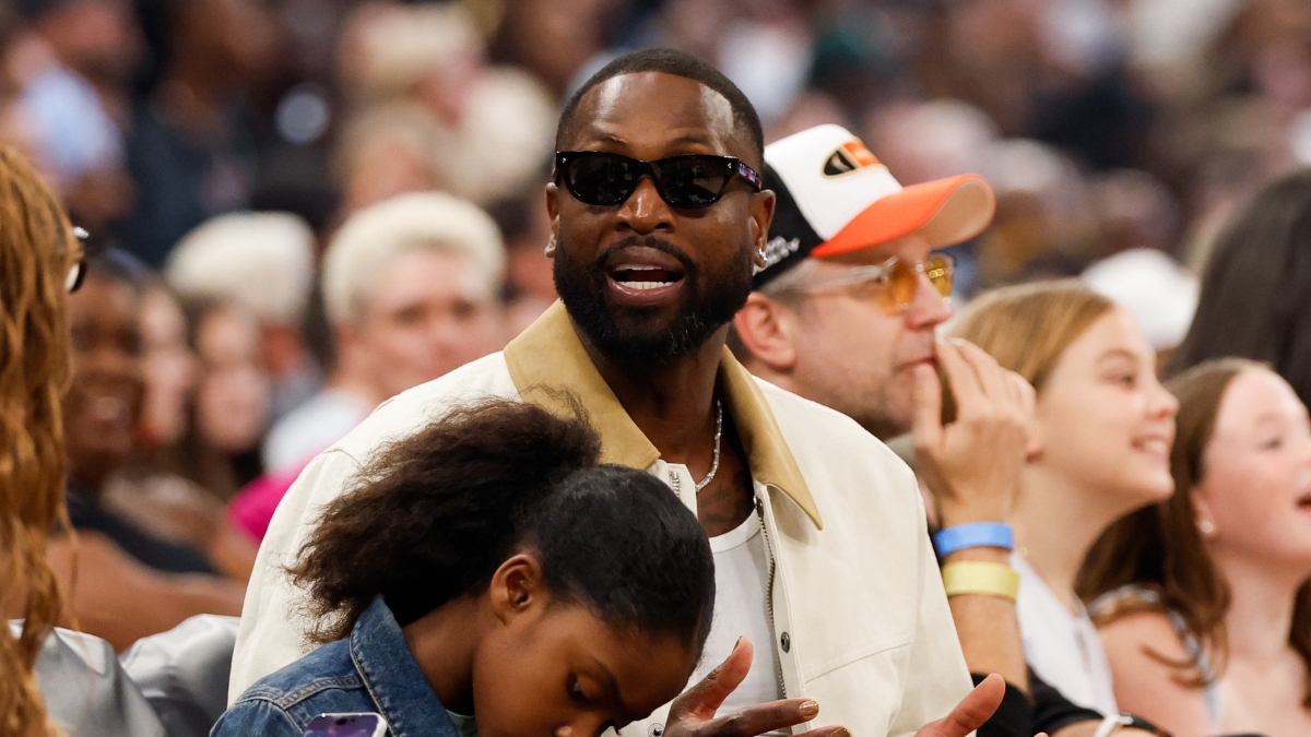 Dwyane Wade sits courtside in sunglasses and a cream jacket during the 2026 WNBA All-Star Game at United Center in Chicago.