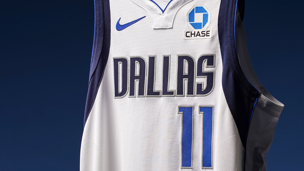 Close-up of a Dallas Mavericks white jersey showing the No. 11 and a new Chase logo patch on the left chest