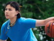 Dallas Wings center Li Yueru palms a Wilson basketball in Under Armour apparel on an outdoor court.