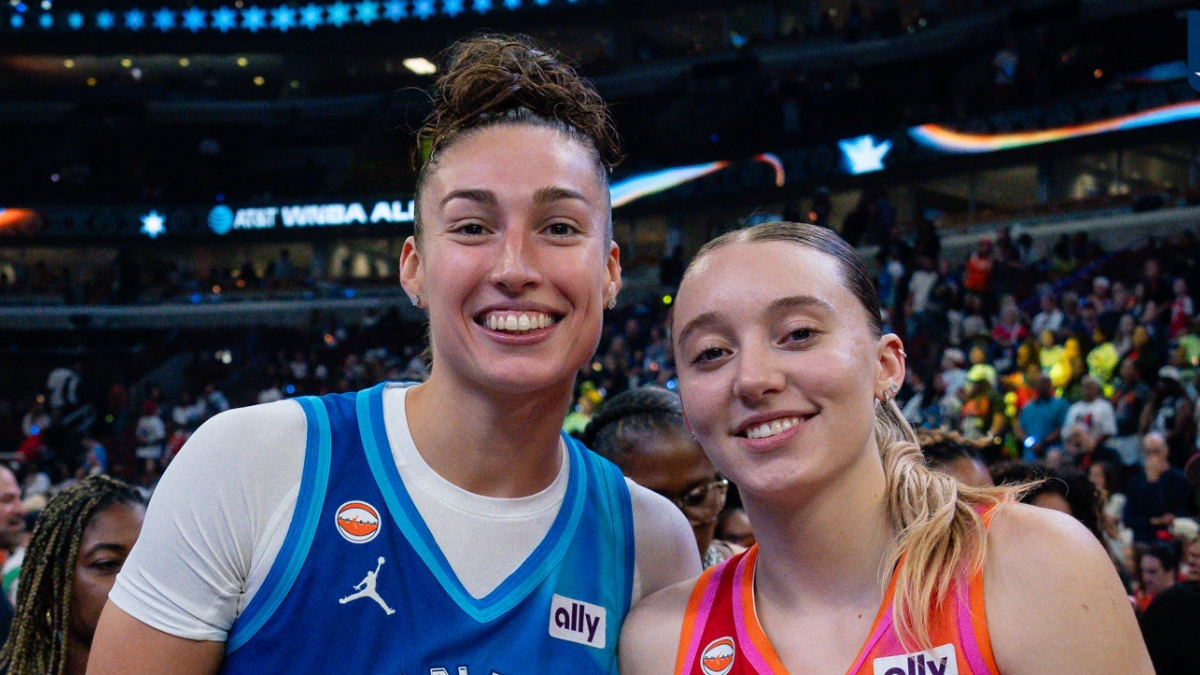 Jessica Shepard, in a blue Team Spoon jersey, and Paige Bueckers, in an orange Team Coop jersey, stand together and smile on the court after the 2026 WNBA All-Star Game.