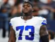 Dallas Cowboys offensive lineman Tyler Smith wearing his No. 73 white jersey and a black skull cap during pregame warmups