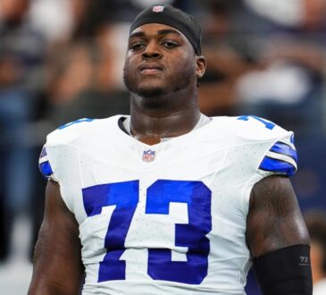Dallas Cowboys offensive lineman Tyler Smith wearing his No. 73 white jersey and a black skull cap during pregame warmups