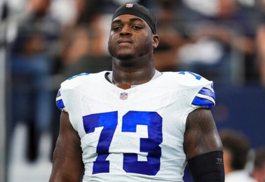 Dallas Cowboys offensive lineman Tyler Smith wearing his No. 73 white jersey and a black skull cap during pregame warmups