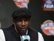 Amar'e Stoudemire speaks into an NCAA microphone at the Naismith Hall of Fame press conference in a flat cap and black vest.