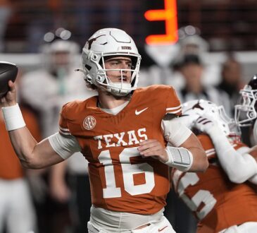 Texas Longhorns quarterback Arch Manning cocks his arm to throw with a Texas A&M rush closing behind him.