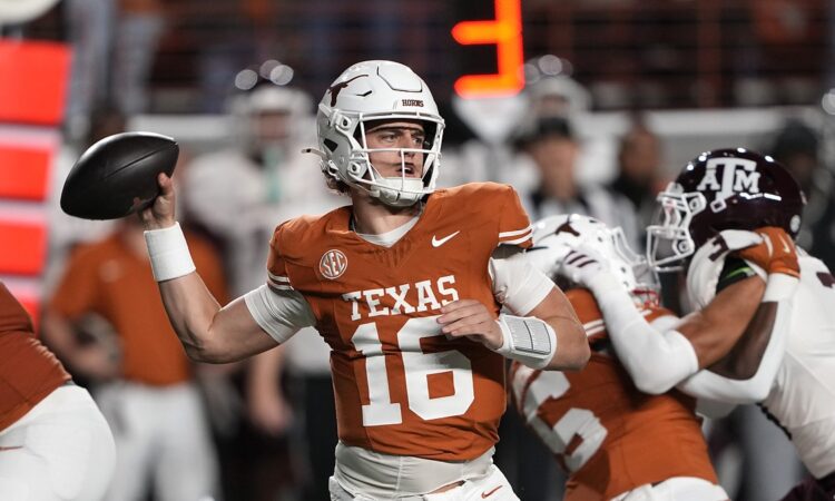 Texas Longhorns quarterback Arch Manning cocks his arm to throw with a Texas A&M rush closing behind him.
