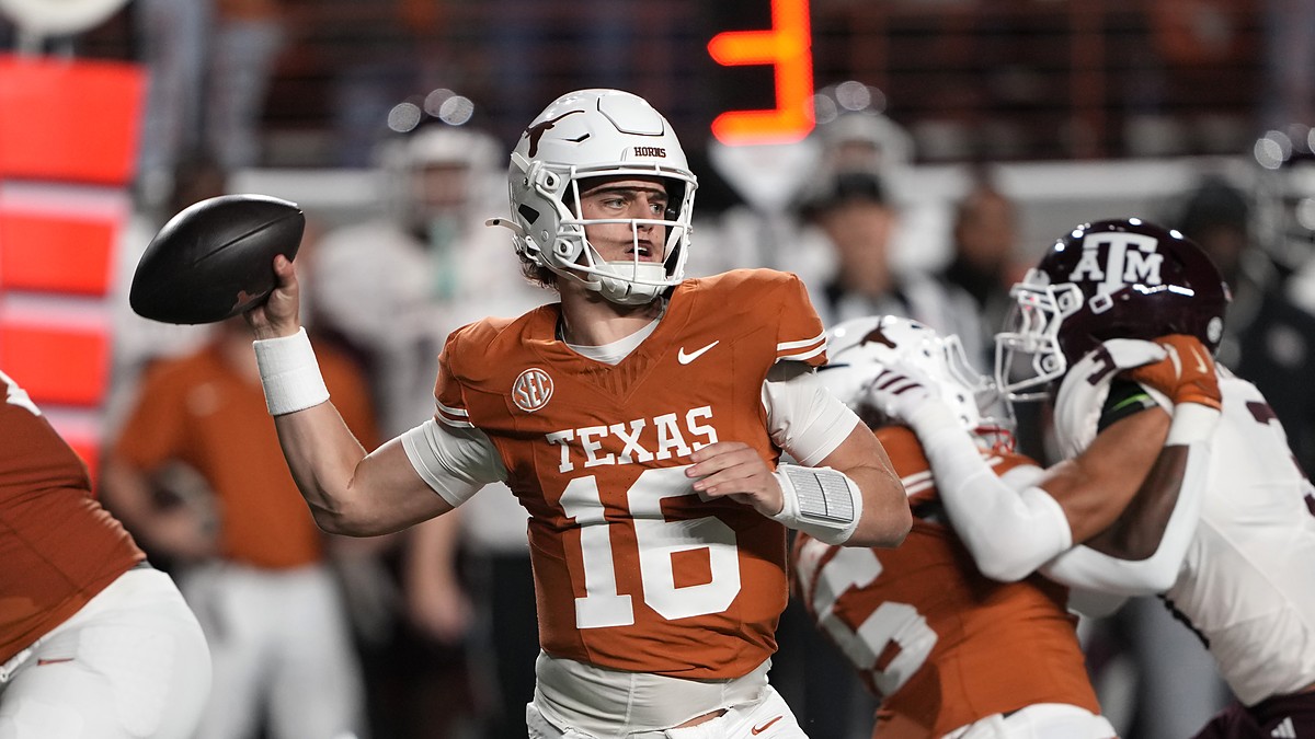 Texas Longhorns quarterback Arch Manning cocks his arm to throw with a Texas A&M rush closing behind him.