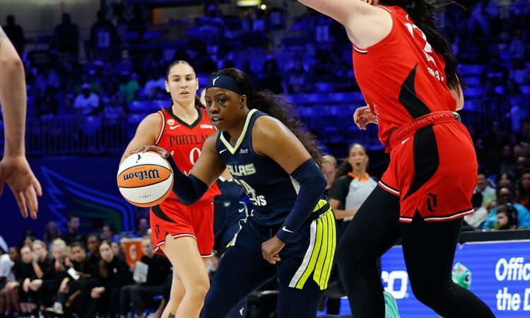Dallas Wings guard Arike Ogunbowale drives the ball toward the basket past a Portland Fire defender.