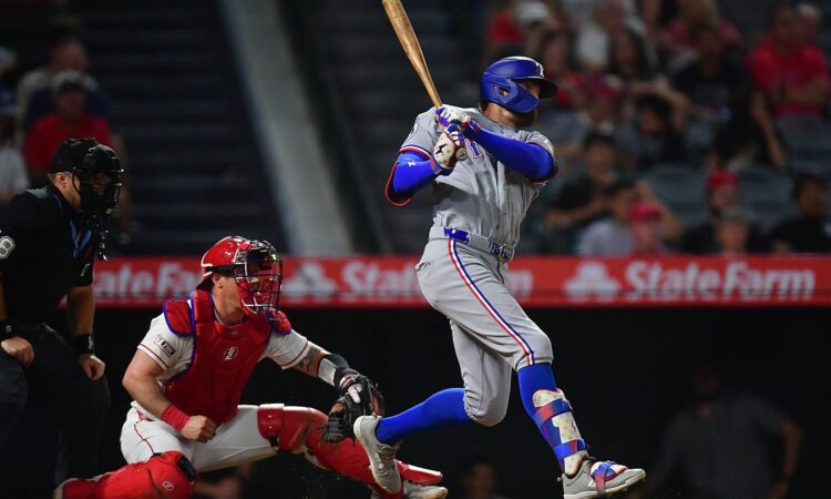 Texas Rangers right fielder Brandon Nimmo follows through on a swing as the Angels catcher watches from his knees.