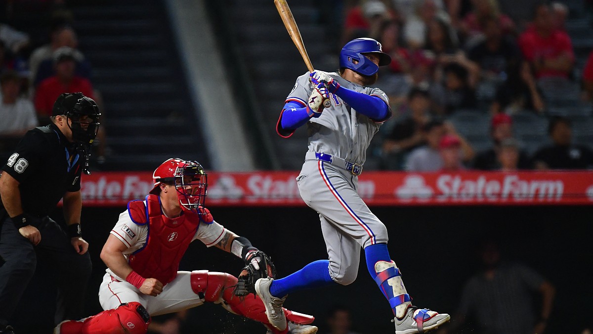 Texas Rangers right fielder Brandon Nimmo follows through on a swing as the Angels catcher watches from his knees.