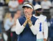 Dallas Cowboys head coach Brian Schottenheimer claps as he watches pregame warmups on the field.