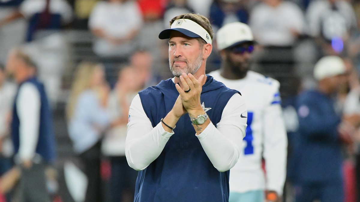 Dallas Cowboys head coach Brian Schottenheimer claps as he watches pregame warmups on the field.
