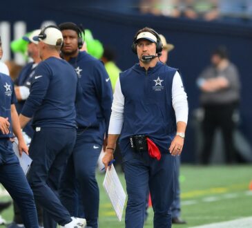 Dallas Cowboys head coach Brian Schottenheimer walks the sideline in a headset, holding a play sheet.