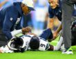 Seattle Seahawks trainers kneel over safety Bud Clark on the field after a leg injury.