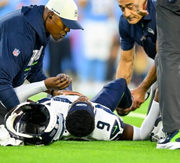 Seattle Seahawks trainers kneel over safety Bud Clark on the field after a leg injury.