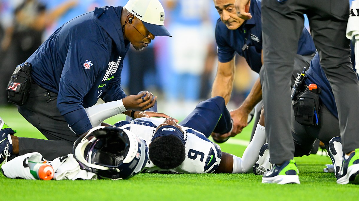 Seattle Seahawks trainers kneel over safety Bud Clark on the field after a leg injury.
