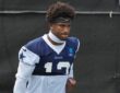 Dallas Cowboys safety Caleb Downs walks the practice field in a navy No. 13 practice jersey and headband.