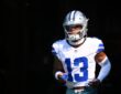 Dallas Cowboys safety Caleb Downs runs out of the tunnel in his white No. 13 jersey, mouthguard in hand.