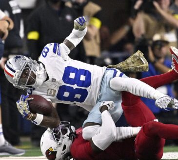 Dallas Cowboys wide receiver CeeDee Lamb reaches out with the ball as Arizona Cardinals cornerback Will Johnson tackles him.